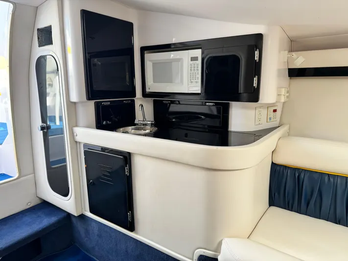  Yacht Photos Pics 2004 Donzi 38 ZX interior with kitchenette, featuring microwave, sink, and storage cabinets.