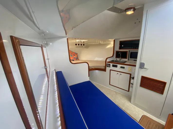  Yacht Photos Pics Interior of 1995 L&H 33 boat with blue seating and compact kitchen area.