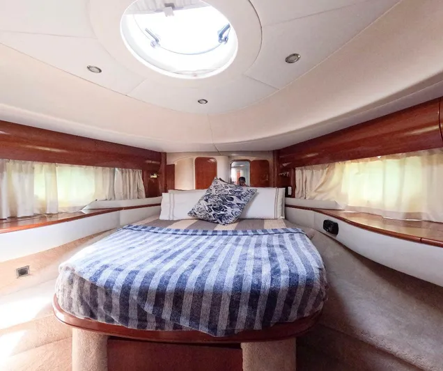 2004 Princess 65 @ Cancun Incentive Yacht Photos Pics Luxurious cabin interior of a 2004 Princess 65 yacht with cozy bedding and elegant wood finishes.