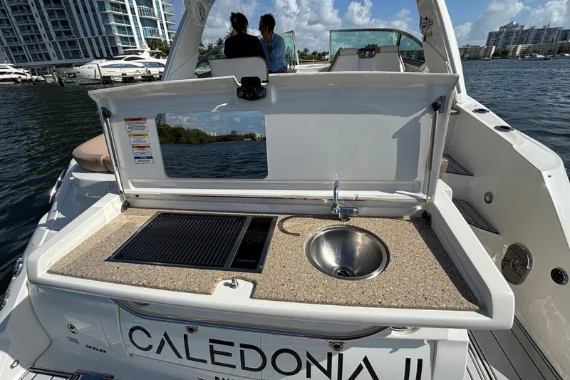  Yacht Photos Pics 2016 Sea Ray 350 Sundancer yacht with outdoor kitchenette and sink, docked near luxury buildings.
