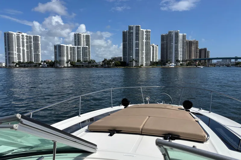  Yacht Photos Pics 2016 Sea Ray 350 Sundancer cruising near waterfront skyscrapers under a clear blue sky.