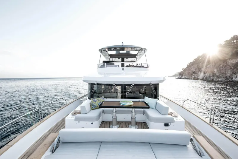  Yacht Photos Pics Luxurious 2022 Sirena 68 yacht on serene waters near a rocky coastline.