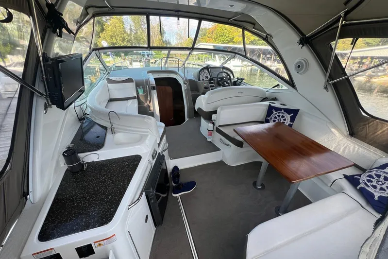  Yacht Photos Pics 2008 Cruisers Yachts 330 Express interior with seating, table, and helm, docked by water.