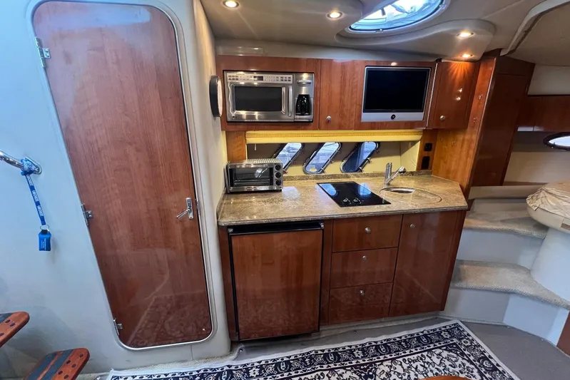  Yacht Photos Pics 2008 Cruisers Yachts 330 Express interior kitchen with wood cabinetry and modern appliances.