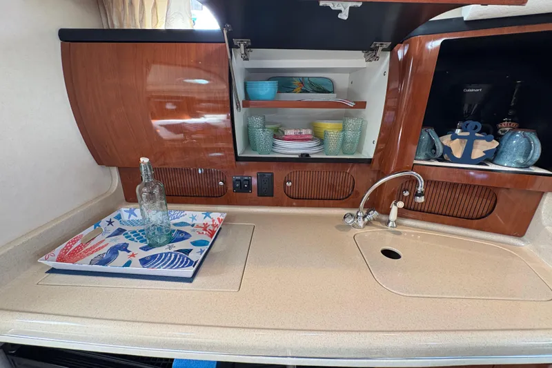 Devocean Yacht Photos Pics 2003 Sea Ray 360 Sundancer kitchen with wooden cabinets, sink, and colorful dishware.