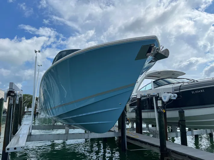 Big Sea Yacht Photos Pics 2020 Cobia 350 Center Console boat on lift, blue hull, marina setting, cloudy sky.