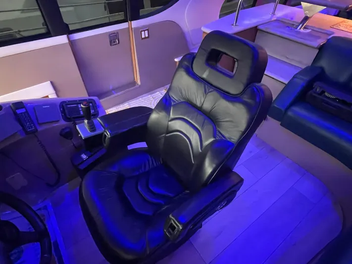 Relentless Yacht Photos Pics Luxurious leather captain's chair in 1998 Carver 530 Voyager Pilothouse, illuminated by blue lighting.