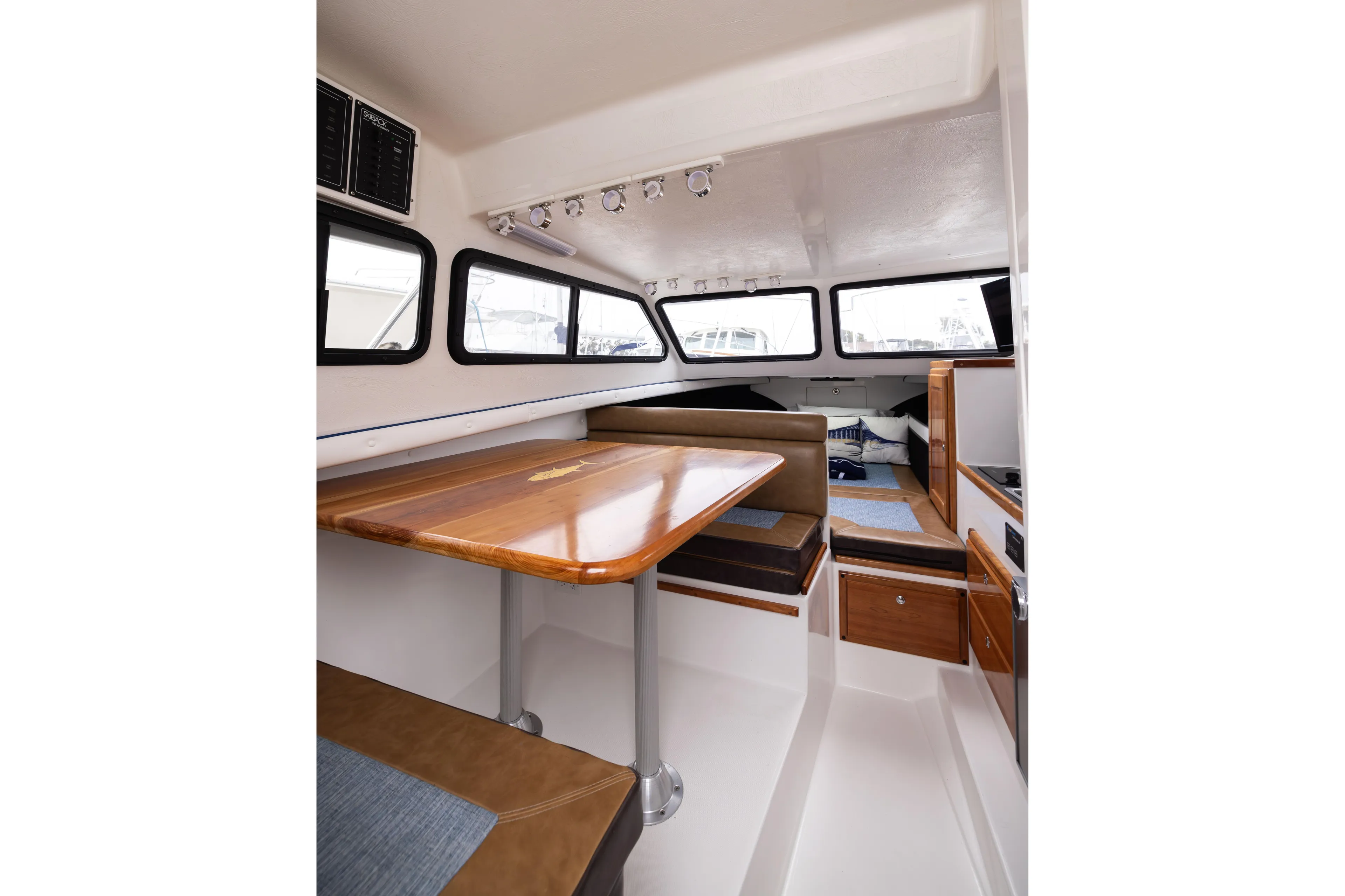 5th Kid Yacht Photos Pics Interior of 2023 Skipjack 26 Flybridge boat with wooden table and seating area.