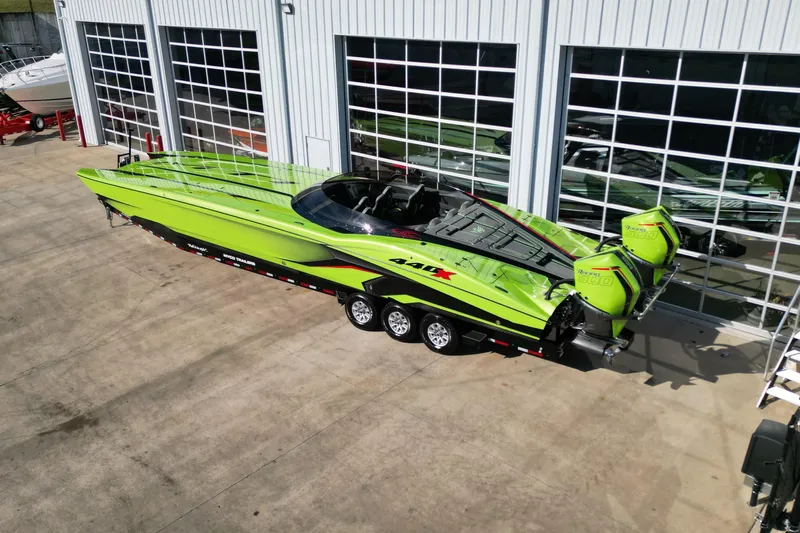  Yacht Photos Pics Bright green 2025 MTI 440X powerboat with dual engines on a trailer outside a garage.