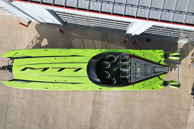  Yacht Photos Pics Aerial view of 2025 MTI 440X speedboat in vibrant green, docked beside a building.