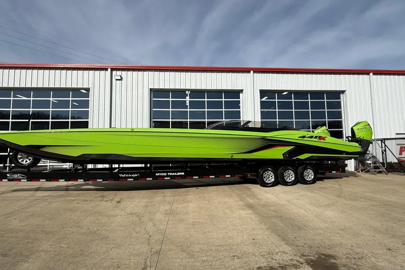  Yacht Photos Pics Bright green 2025 MTI 440X powerboat on trailer, parked outside industrial building.