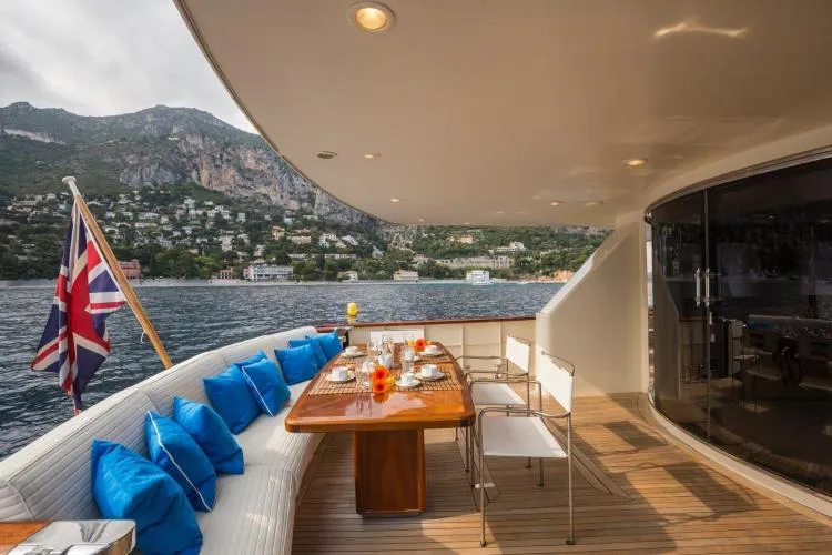  Yacht Photos Pics Luxurious 1999 Alalunga Navetta 30 yacht deck with dining area, scenic coastal view.