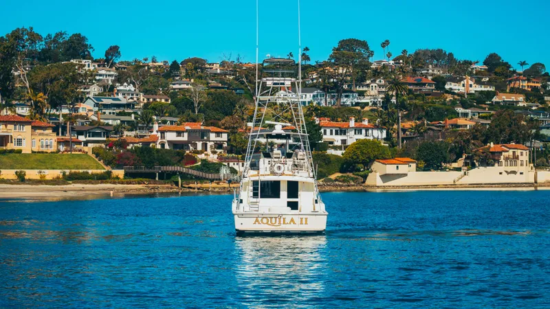 Aquila II Yacht Photos Pics 1990 Bertram 50 Convertible boat "Aquila II" on water with scenic coastal homes in background.