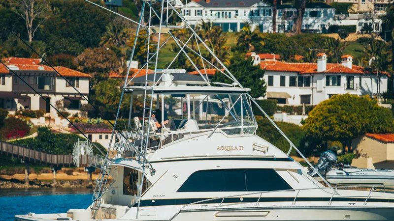 Aquila II Yacht Photos Pics 1990 Bertram 50 Convertible yacht docked near luxury waterfront homes.