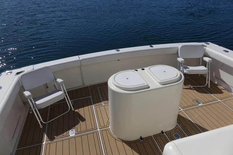 Aquila II Yacht Photos Pics Bertram 50 Convertible 1990 yacht deck with chairs and storage, overlooking calm water.