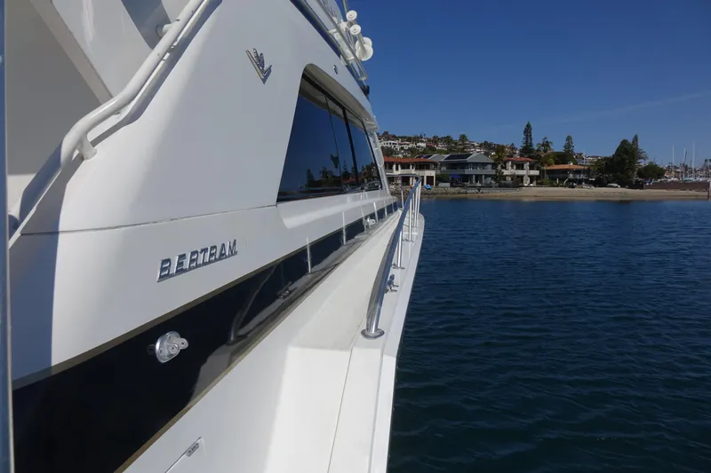 Aquila II Yacht Photos Pics 1990 Bertram 50 Convertible yacht on calm water near shoreline.