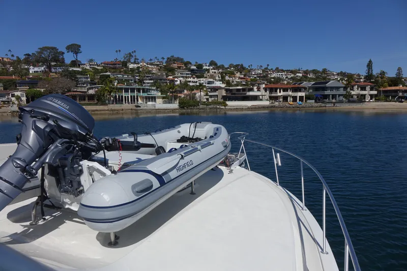 Aquila II Yacht Photos Pics Bertram 50 Convertible yacht with dinghy, 1990 model, docked near waterfront homes.