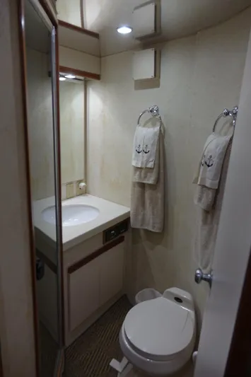 Aquila II Yacht Photos Pics 1990 Bertram 50 Convertible yacht bathroom with sink, toilet, and nautical-themed towels.