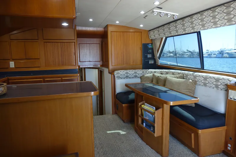 Aquila II Yacht Photos Pics Interior of a 1990 Bertram 50 Convertible yacht with wood finishes and a waterfront view.
