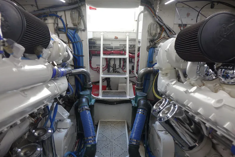 Aquila II Yacht Photos Pics Engine room of a 1990 Bertram 50 Convertible yacht, showcasing dual engines and mechanical components.