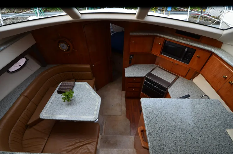 Radio Wave Yacht Photos Pics Interior of 2001 Carver 406 yacht with kitchen and dining area, featuring wood cabinetry and seating.
