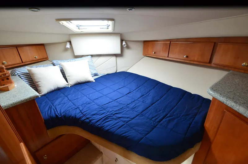 Radio Wave Yacht Photos Pics Cozy cabin interior of 2001 Carver 406 yacht with blue bedding and wooden cabinets.