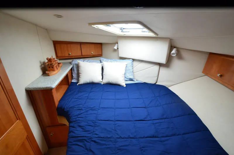 Radio Wave Yacht Photos Pics Cozy cabin interior of 2001 Carver 406 yacht with blue bedding and wooden cabinets.