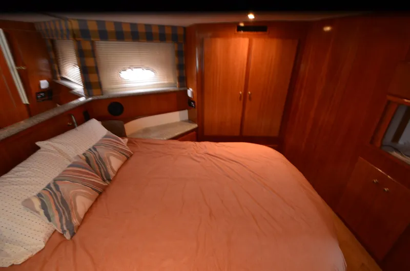 Radio Wave Yacht Photos Pics Interior of 2001 Carver 406 yacht bedroom with cozy bed and wooden cabinetry.