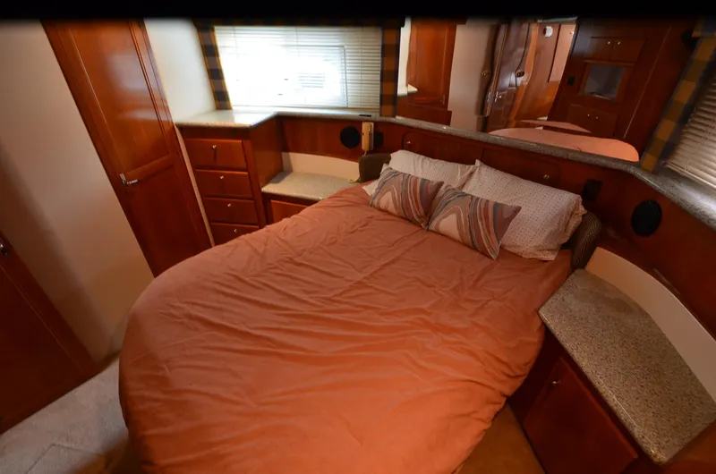 Radio Wave Yacht Photos Pics Interior of 2001 Carver 406 yacht bedroom with cozy bed and wooden cabinetry.