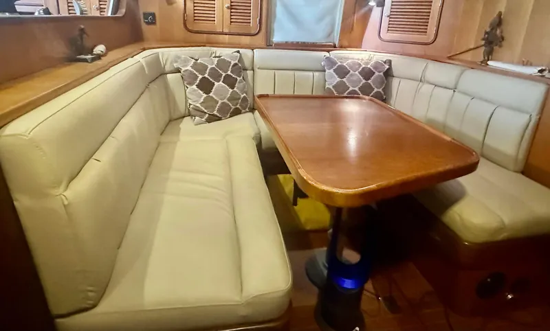 Joy Yacht Photos Pics Cozy dining area in 1999 Passport Royal 43 yacht with cushioned seating and wooden table.