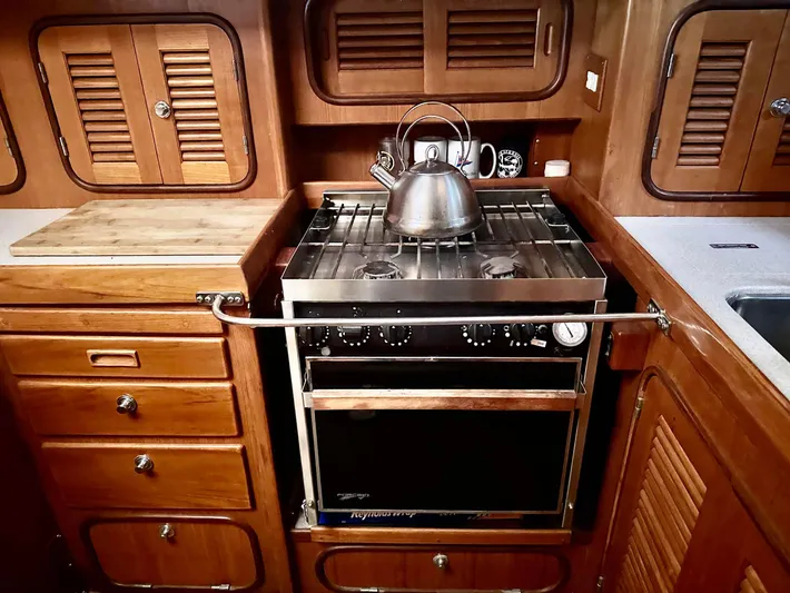 Joy Yacht Photos Pics Wooden yacht kitchen with stove, kettle, and cabinets in a 1999 Passport Royal 43.