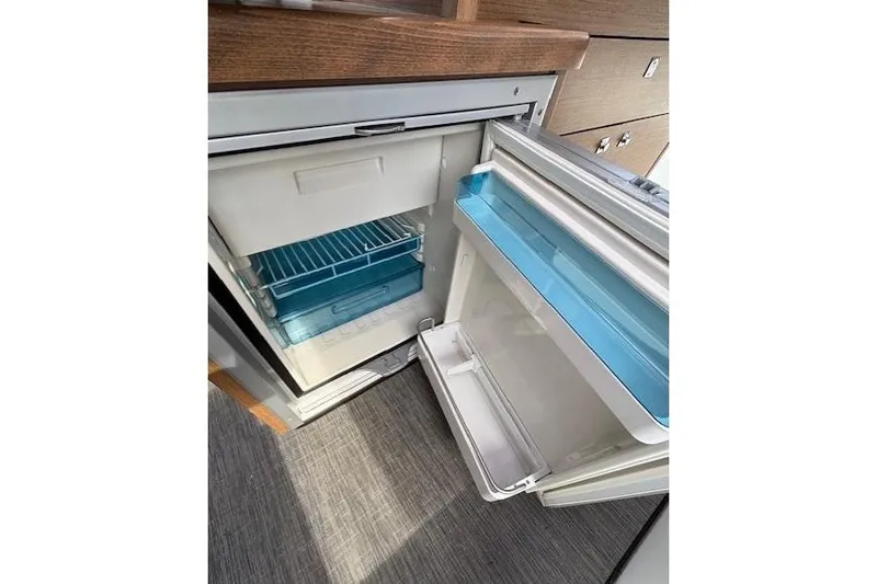  Yacht Photos Pics Open refrigerator inside 2021 Jeanneau NC Sport 895 boat, featuring blue shelves.