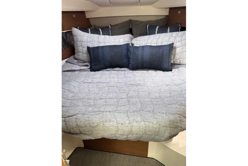  Yacht Photos Pics Cozy cabin bed in 2021 Jeanneau NC Sport 895 boat, featuring elegant bedding.
