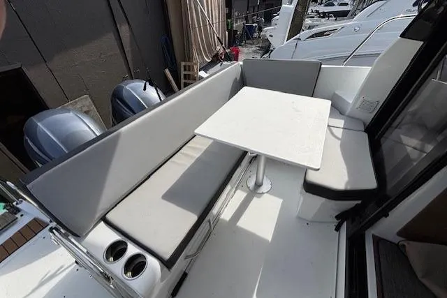  Yacht Photos Pics 2021 Jeanneau NC Sport 895 boat interior with cushioned seating and table.