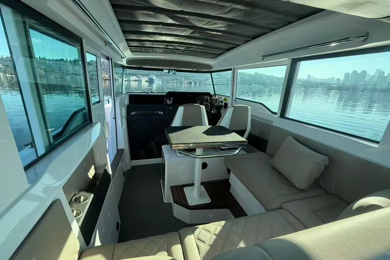 Yacht Photos Pics Interior of 2022 Axopar 37 XC Cross Cabin with seating and table, overlooking water.