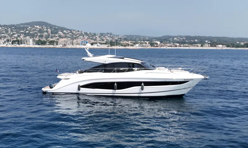  Yacht Photos Pics 2024 Princess V55 yacht cruising on blue ocean near coastal town.