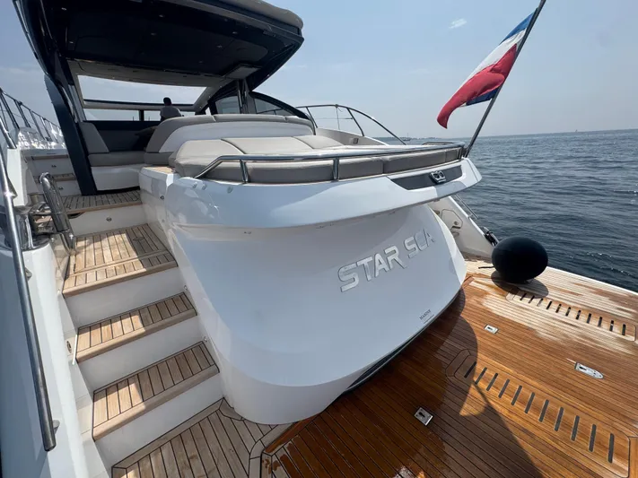  Yacht Photos Pics 2024 Princess V55 yacht with wooden deck and flag, cruising on open water.