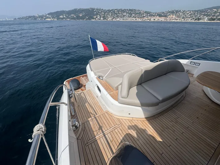  Yacht Photos Pics 2024 Princess V55 yacht deck with French flag, overlooking serene coastal waters.