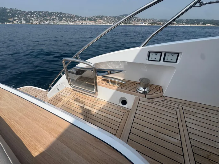 Yacht Photos Pics 2024 Princess V55 yacht deck with sleek wood finish, overlooking serene coastal waters.