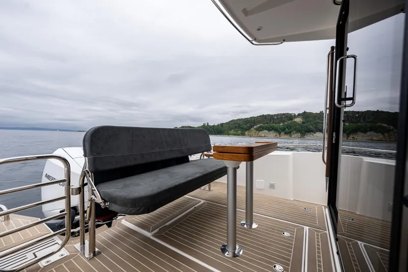 #41 Trade In Yacht Photos Pics Nimbus C11 2022 boat deck with seating and table, overlooking serene waters and lush coastline.