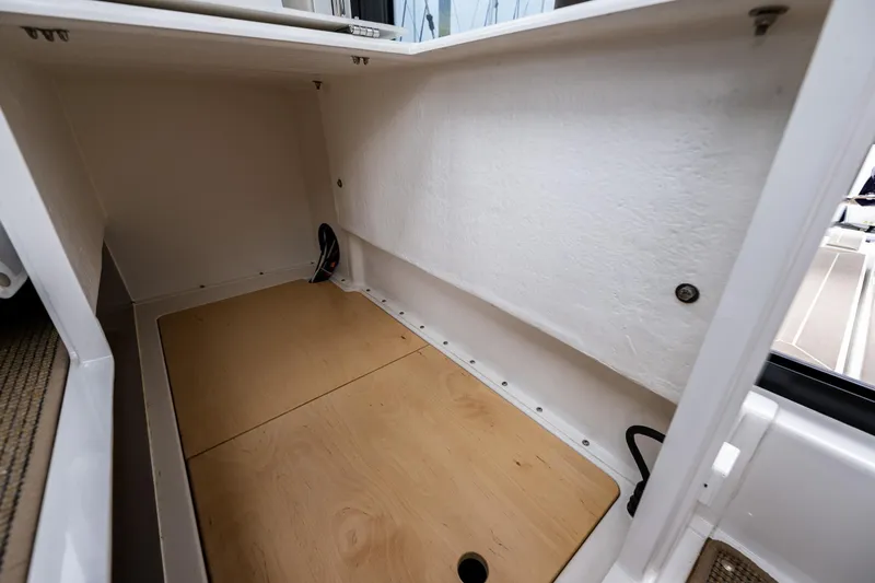 #41 Trade In Yacht Photos Pics Storage compartment in a 2022 Nimbus C11 boat, featuring a wooden base and white interior.
