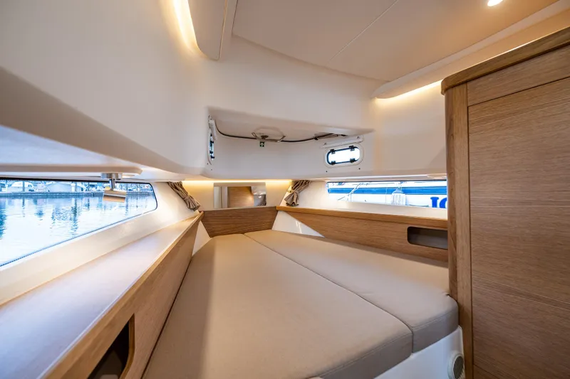 #41 Trade In Yacht Photos Pics Luxurious interior cabin of 2022 Nimbus C11 boat with modern wood finish and cozy bedding.