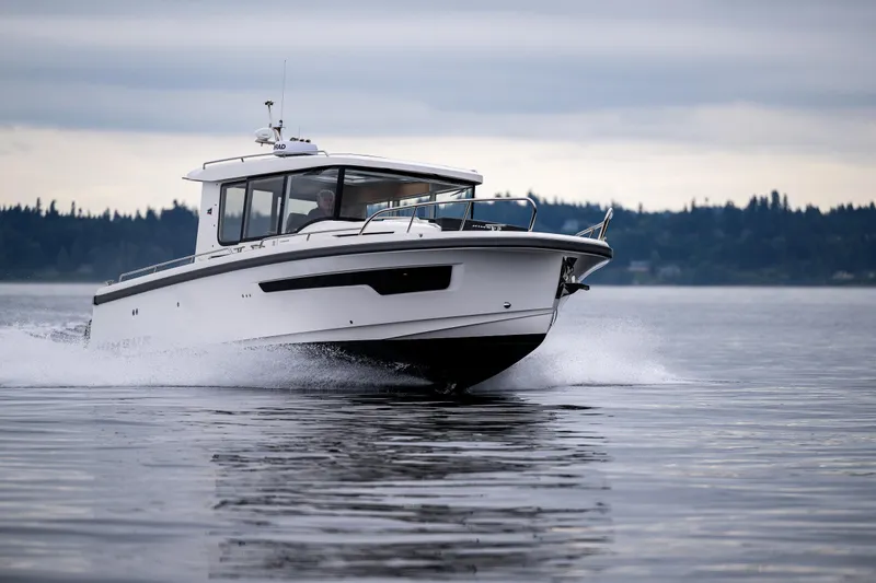 #41 Trade In Yacht Photos Pics Nimbus C11 2022 boat cruising on calm water with forested shoreline in background.