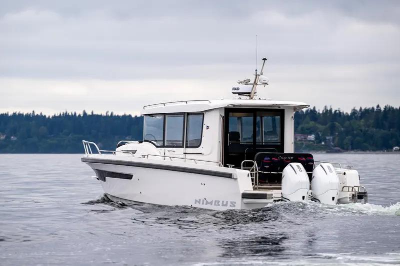 #41 Trade In Yacht Photos Pics 2022 Nimbus C11 boat cruising on a calm lake with forested shoreline.