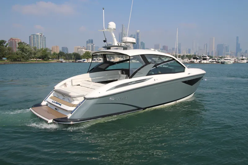  Yacht Photos Pics 2018 Cobalt A36 boat cruising near city skyline on a sunny day.