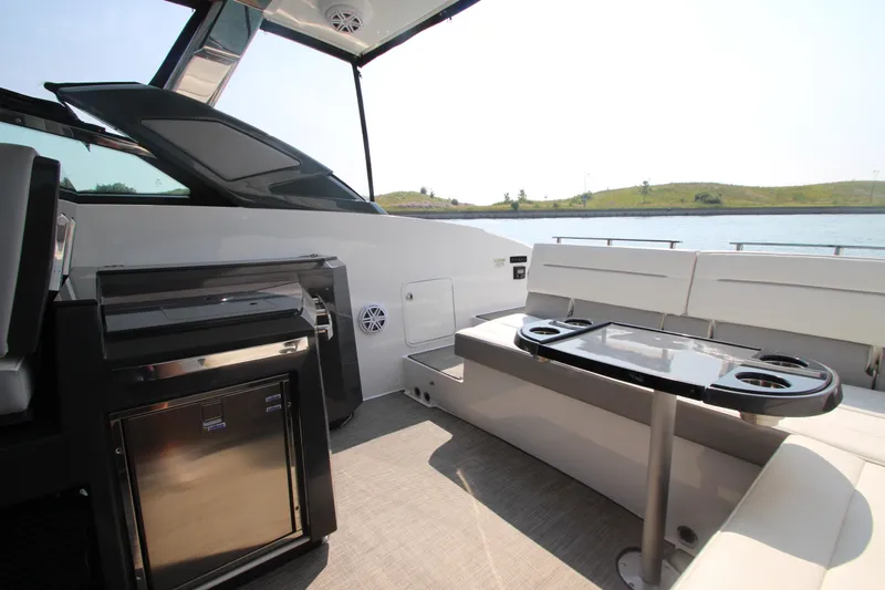 Yacht Photos Pics 2018 Cobalt A36 boat interior with seating, table, and mini-fridge, near water.