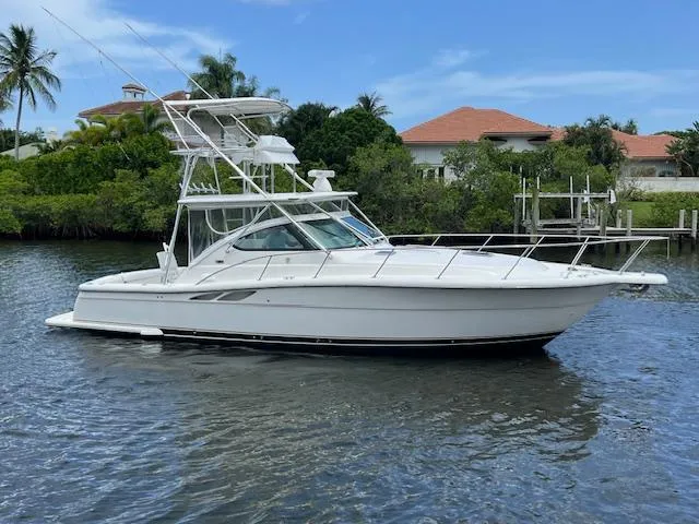  Yacht Photos Pics 2003 Tiara Yachts 3800 Open boat on calm water, surrounded by lush greenery.