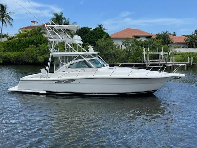  Yacht Photos Pics 2003 Tiara Yachts 3800 Open boat on calm water, surrounded by lush greenery.