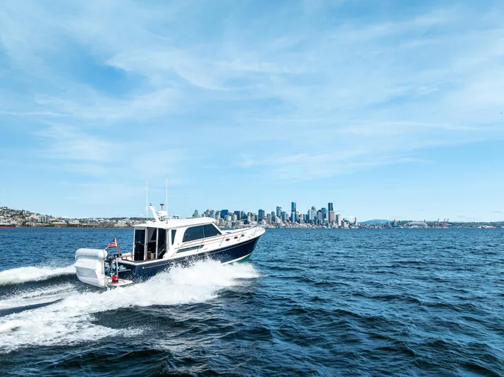 Tangled Up In Blue Yacht Photos Pics 2013 Back Cove 37 cruising on open water with city skyline in background.