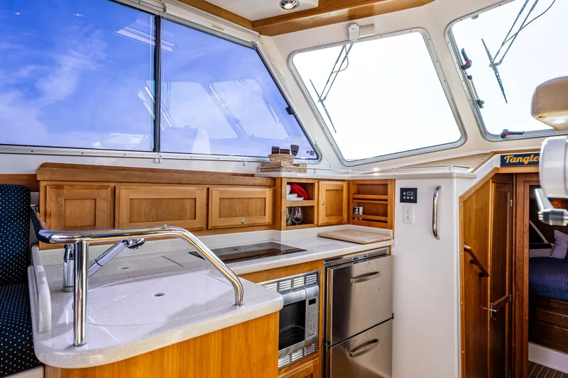Tangled Up In Blue Yacht Photos Pics Interior of 2013 Back Cove 37 yacht, featuring modern kitchen with wood cabinetry and stainless appliances.
